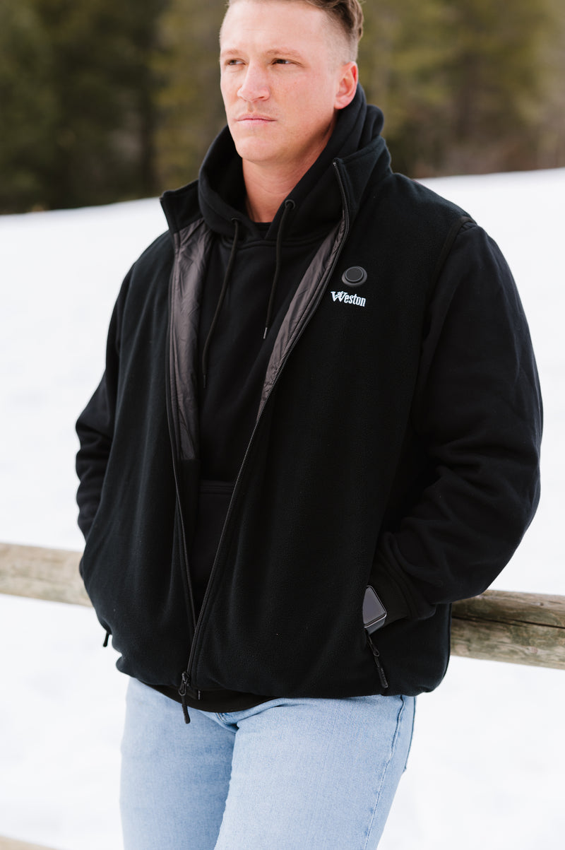 Man wearing a black hoodie and jacket with Weston logo, standing outdoors in a snowy landscape.